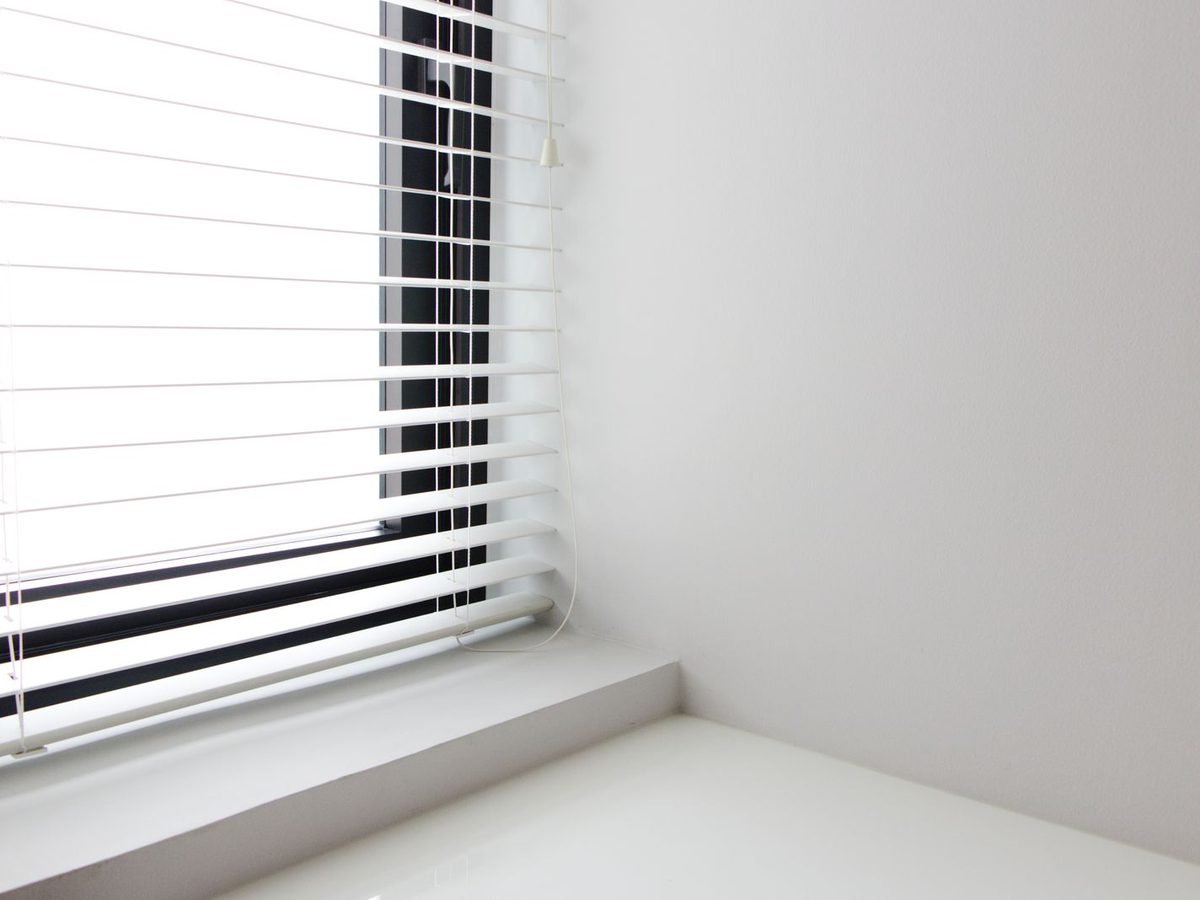 White Venetian blind in a bright room corner.