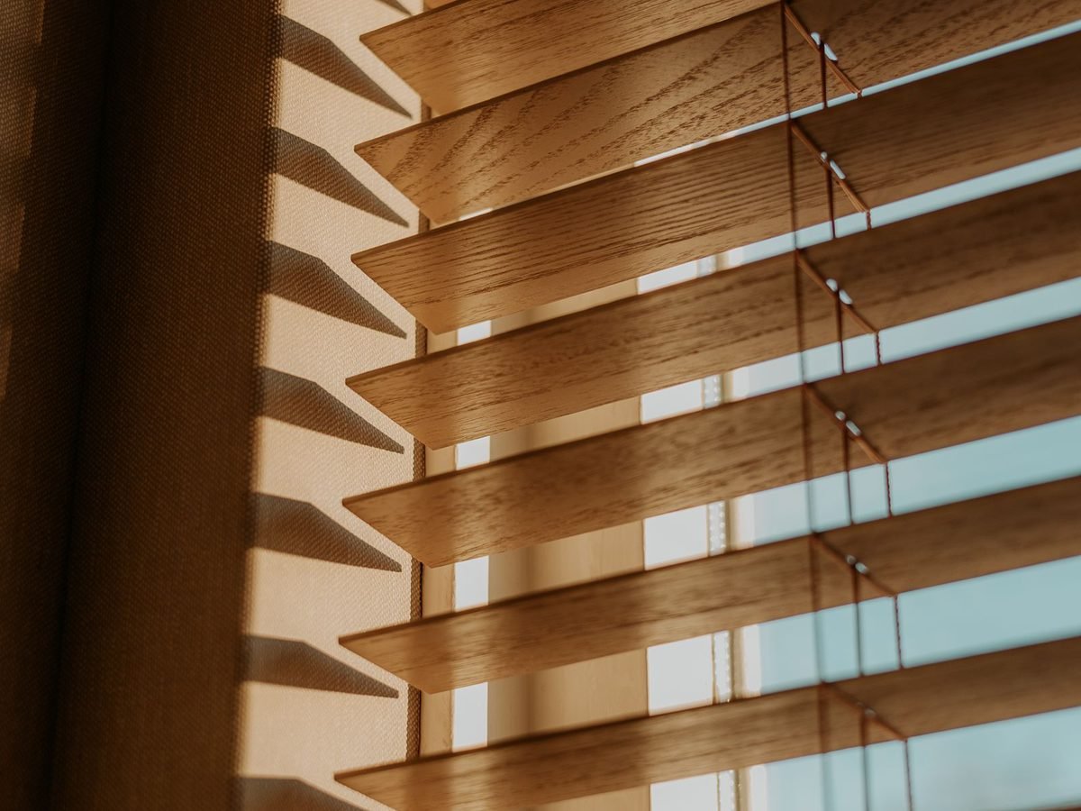 Warm wooden Venetian blinds filtering sunlight.