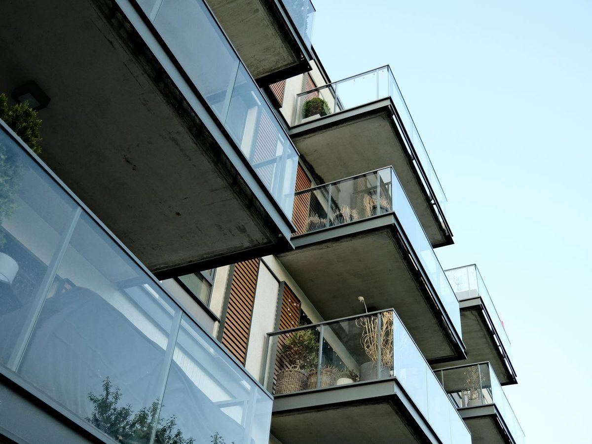 Modern apartment balconies with clear glass safety railings.